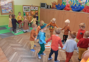 Dzieci tańczą w dwóch kołach dookoła obrazków przedstawiających warzywa